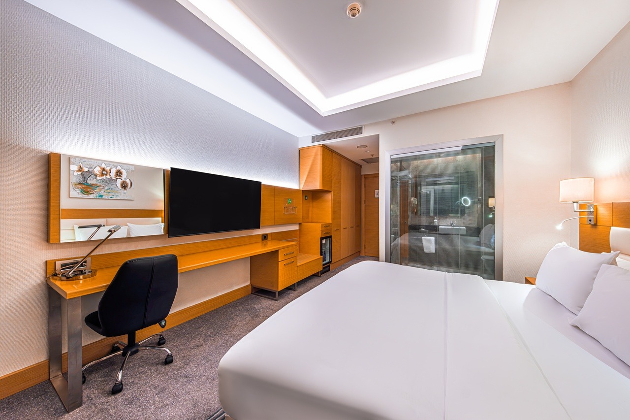 Hotel room with one king-size bed, a desk and a wall-mounted TV