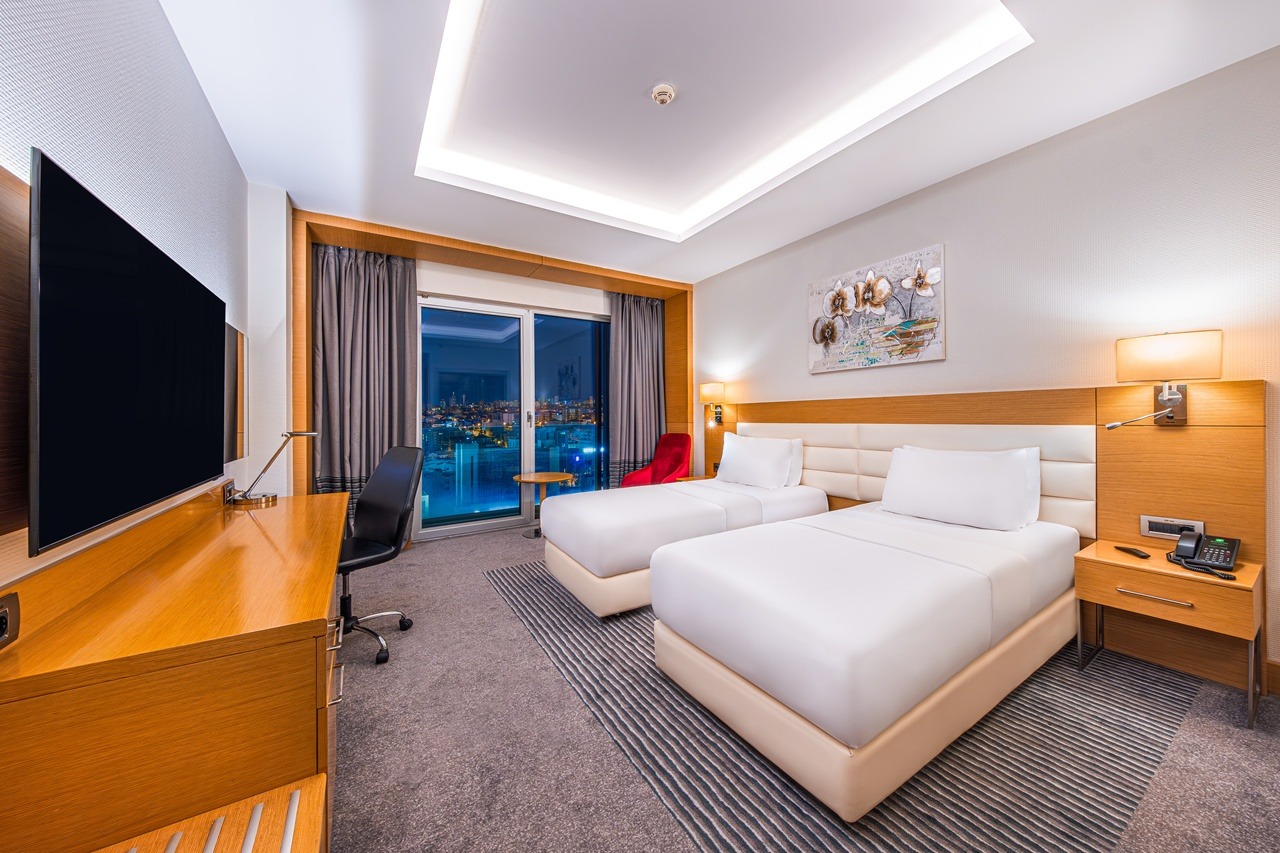 Hotel room with two single beds and a city view through the window