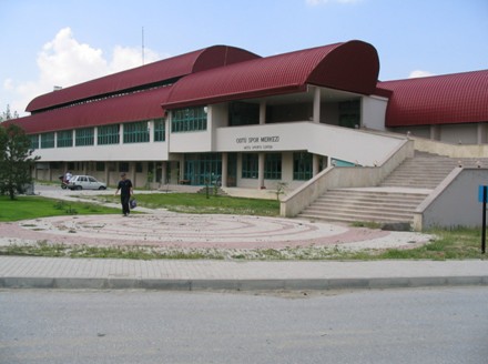 ODTÜKENT Sports Hall from outside: a long low building with a curved red roof and a wide stair up to the entrance